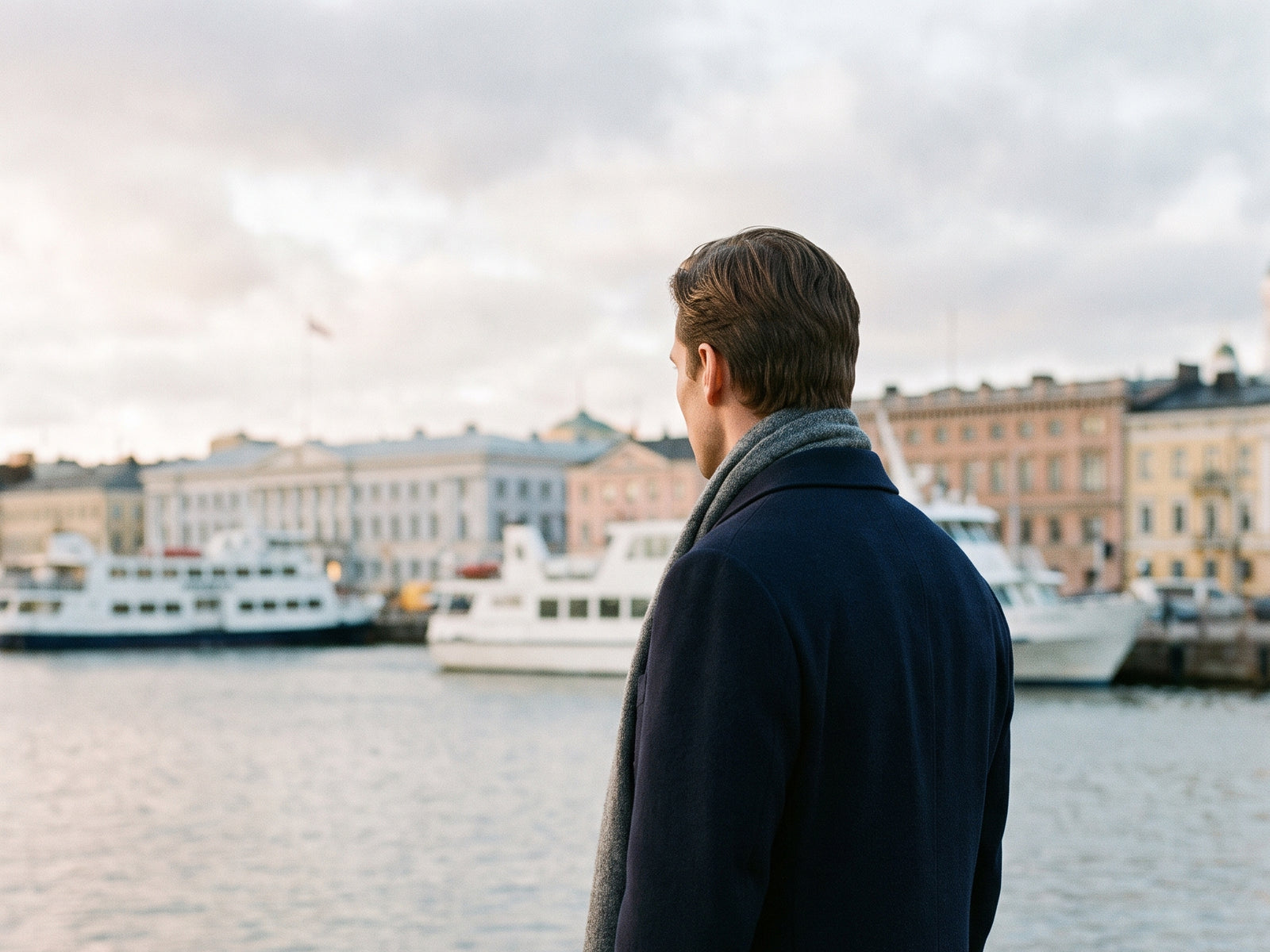 Mies tummansinisessä villakangastakissa Helsingin Etelärannassa