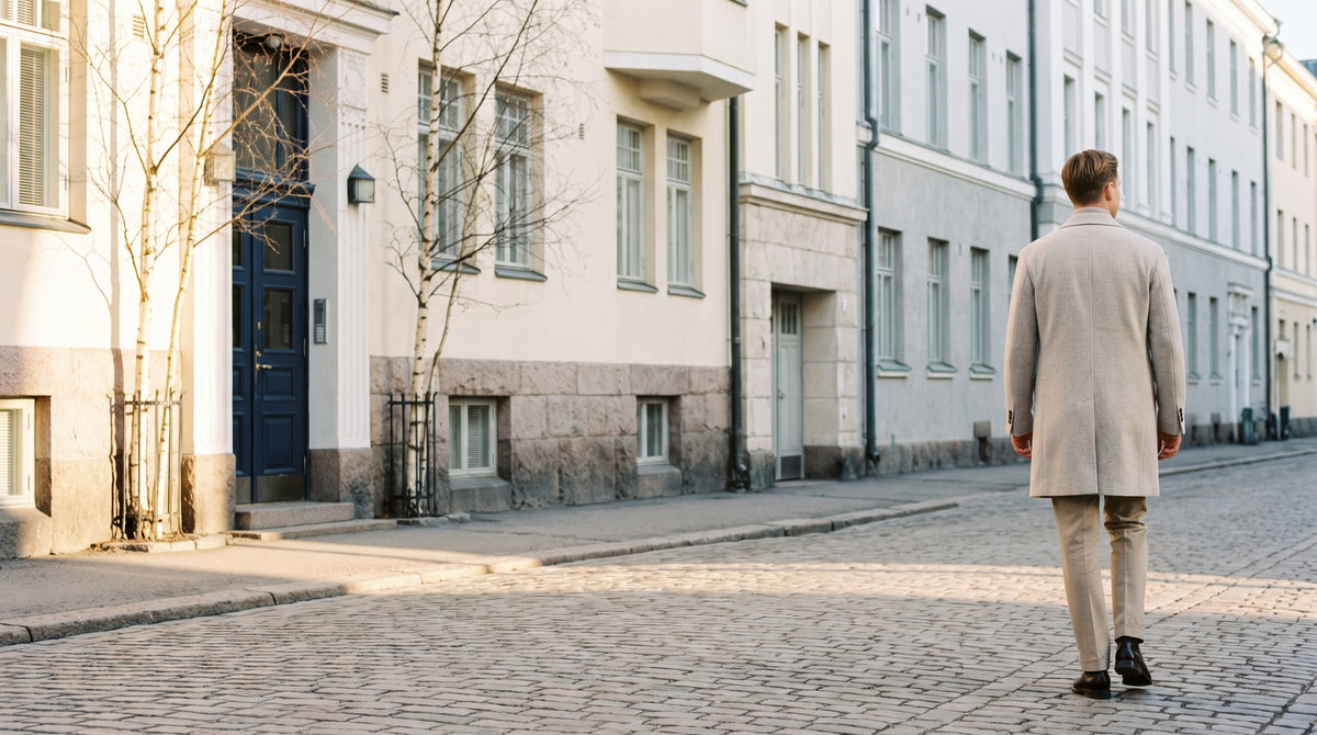 Mies vaaleassa villakangastakissa kävelee aamuauringossa Helsingin kadulla